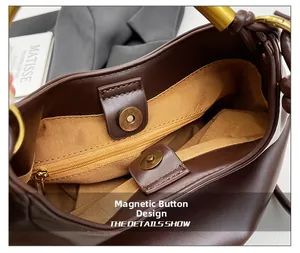 Detail of magnetic buckle closure and zip pocket in dark brown leather handbag