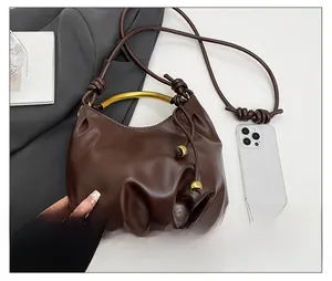 Detailed view of brown leather cloud bag with gold handle and phone for size reference