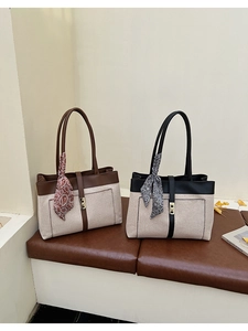 Detail of minimalist tote bags with silk scarves and metal buckles on a leather bench