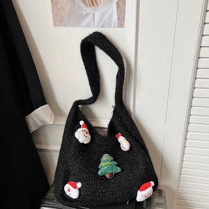 Black knit tote bag with Santa and Christmas tree patches on a dark suitcase
