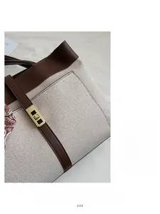 Detail of beige canvas tote bag with brown leather trim and decorative silk scarf
