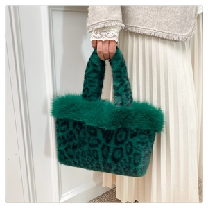 Détail d'un sac à main en fausse fourrure léopard vert foncé avec des poignées en peluche