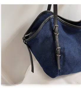 Close-up of the vintage blue denim tote bag featuring black leather trim and silver metal hardware