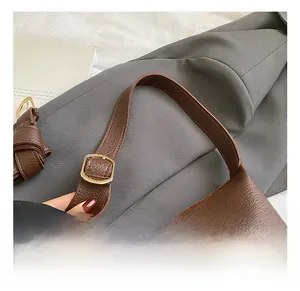 Close-up of brown litchi leather handbag strap with adjustable gold buckle detail