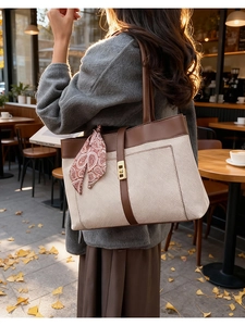 Detail of beige tote bag with brown leather trim and decorative paisley scarf handle