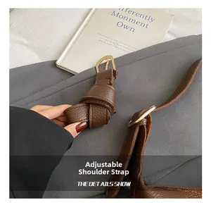 Detail of adjustable shoulder strap with gold hardware on brown lychee texture leather bag