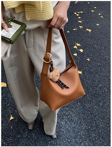 Detail of caramel leather shoulder bag with gold buckle and cute brown bear charm