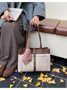 Detail of canvas tote bag with brown leather trim and decorative silk scarf detail