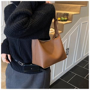Chic brown leather crossbody bag with lychee texture shown in a minimalist studio setting
