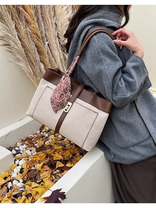 Close-up of canvas tote bag with leather trim and decorative paisley scarf on handle