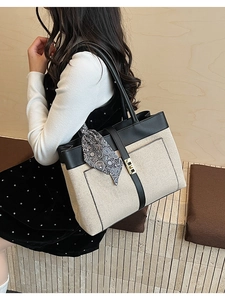 Detail of canvas tote bag with black leather trim and decorative paisley scarf handle