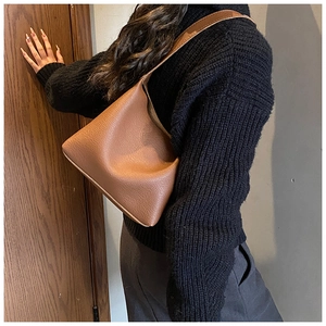 Detail of caramel brown litchi grain leather texture on a minimalist shoulder bag