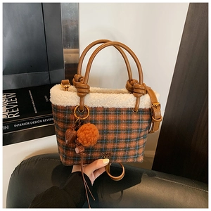Detail of plaid wool handbag with fleece trim, leather handles and decorative pendants