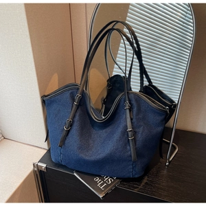 Detail of a large vintage tote bag in dark blue denim with adjustable black leather strap