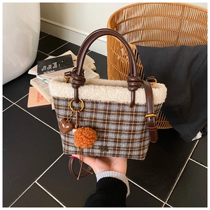 Detail of plaid wool tote bag with white faux fur trim and cute orange pompom charm