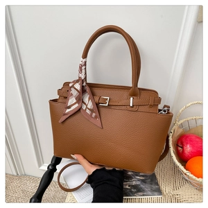 Detailed view of caramel pebble leather tote featuring silver buckle and silk scarf handle