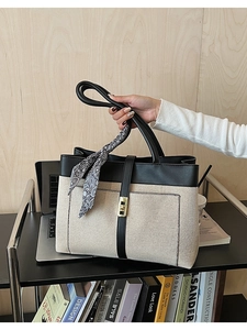 Detail view of canvas tote bag with black leather trim and decorative paisley silk scarf