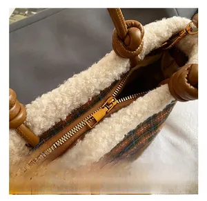 Detail of gold zipper and brown plaid wool fabric with white faux shearling trim