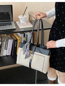 Detail of canvas tote bag with black leather trim and decorative paisley silk scarf
