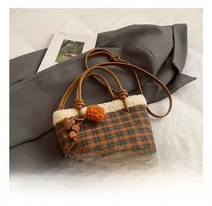 Detail of plaid handbag with wool trim, heart charm, and adjustable crossbody strap