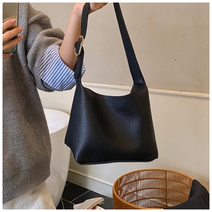 Detail of black pebbled leather texture and gold adjustable buckle on shoulder bag