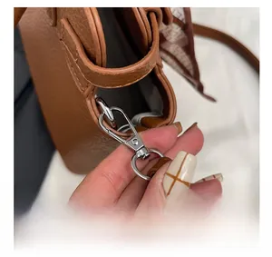 Detail of silver twist-lock hardware on a brown litchi leather handbag with floral scarf