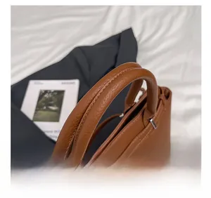 Detail of brown litchi leather handbag featuring silver hardware and silk scarf wrap