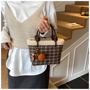 Detail of wool plaid handbag featuring plush faux fur trim and decorative bag charms