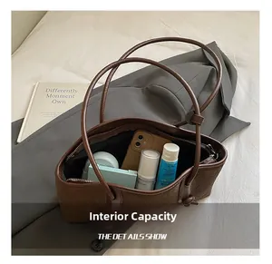 Vue de dessus de l'intérieur spacieux du sac cabas en cuir tressé marron avec accessoires