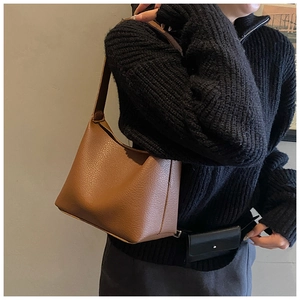 Detail view of brown lychee grain leather shoulder bag worn by model in a minimalist style
