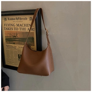 Detail of caramel brown lychee leather texture and metal buckle on crossbody bag