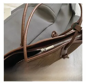 Détail du sac en cuir tressé marron avec fermeture éclair en métal et bandoulière minimaliste