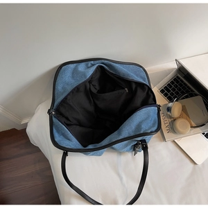 Interior view of denim tote bag showing black fabric lining and zippered pocket