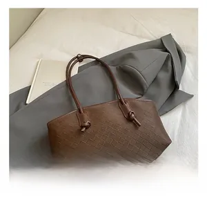 Détail du tressage en cuir marron foncé et de la poignée nouée sur le sac bandoulière