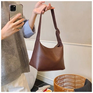 Close-up of dark brown litchi pattern leather texture and metal buckle on hobo bag