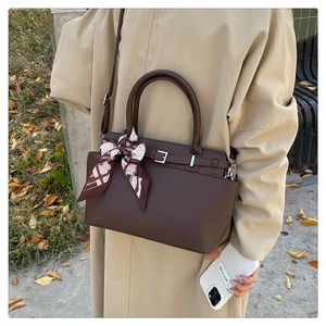 Detail of dark brown pebble leather tote bag with printed silk scarf and crossbody strap