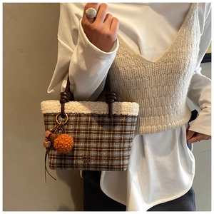 Detail of plaid wool handbag with plush shearling trim and leather knot handle