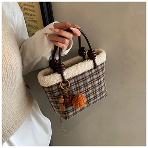 Detail of plaid wool tote bag with white faux fur trim and decorative beaded bag charm