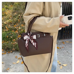 Detail of dark brown lychee leather handbag with decorative scarf and shoulder strap