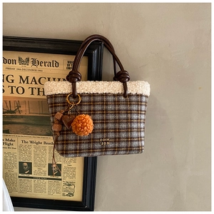 Close-up of checkered wool tote bag featuring plush white trim and decorative heart charm