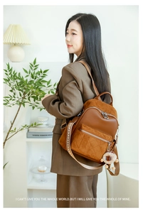 Detail eines braunen Lederrucksacks mit gesteppter Tasche und gewebtem Riemen