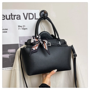 Detail of black lychee grain handbag with silk scarf on handle and silver hardware