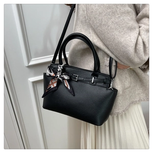 Detail of black litchi grain handbag with a decorative patterned silk scarf on handle