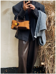 Détail d'un sac à main en daim marron avec pompon et design rétro en patchwork