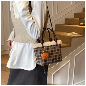 Detail of wool plaid handbag with white faux fur trim and orange pompom charm