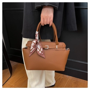 Detail of caramel brown leather tote bag with geometric print silk scarf on handle