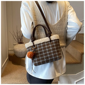Detail of plaid wool tote bag with white faux fur trim and leather handles