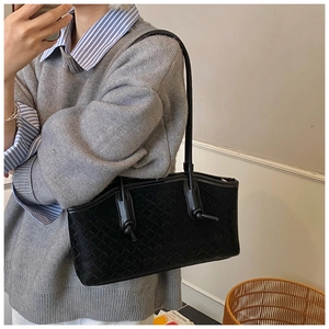 Détail de la texture tressée Intrecciato noire sur un grand sac cabas minimaliste