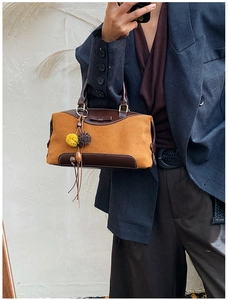 Détail du sac à main rétro en cuir marron avec nœud et breloque porté par un modèle