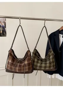 Detail of plaid tote bags with leather trim and decorative bow in brown and green colors